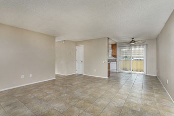 An empty living room with a door to a kitchen